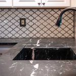 A black soapstone integrated sink with white veins and a patterned backsplash.
