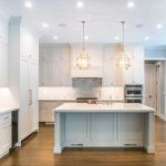 An all white kitchen with white Quartz countertops and brown hardwood floors.